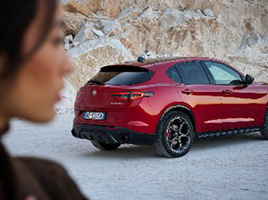 Red SUV parked on a rocky surface with a person's side profile in the foreground.