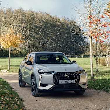 Silver car parked on a countryside road with trees in the background.