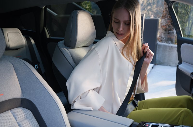 woman putting on seat belt in the front of the car