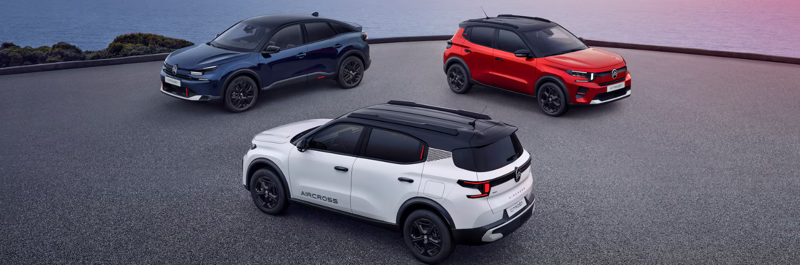 Three cars parked on a grey surface: one white, one red, and one blue.