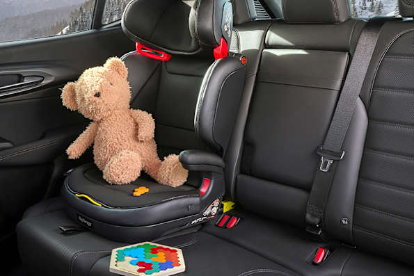 Car interior with teddy bear and puzzle on child booster seat.