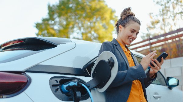 woman sat on next to the car on charge