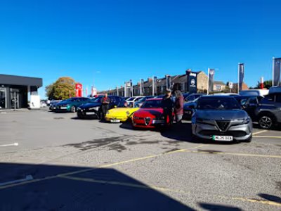 AROC Club parked cars including red, yellow, and grey models in a dealership forecourt.