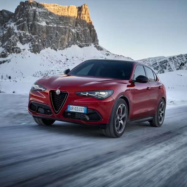 Red Alfa Romeo driving on a snowy Bishop Auckland road for car repairs.