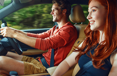 Man and woman smiling while driving a car.