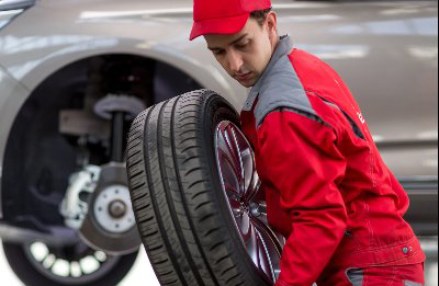 Mechanic in red overalls changing a car tyre.