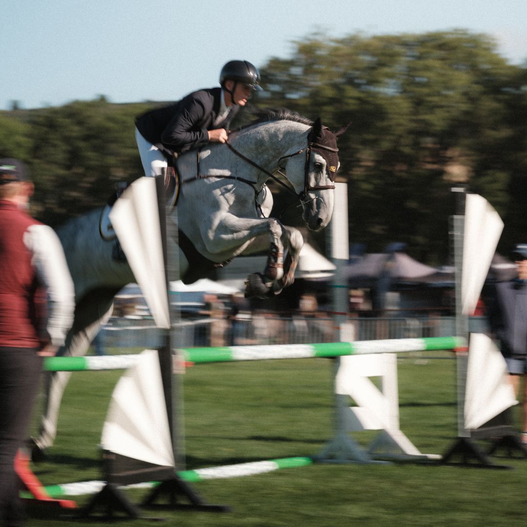 Equestrian jumping over an obstacle during a competition in daytime.